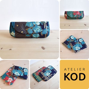 May include: A set of four different fabric pouches with floral patterns in shades of blue, green, and red. The pouches are lined with gold fabric and have a black background. The pouches are labeled "Atelier Kod".