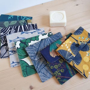 Op de afbeelding: Assortiment van kleurrijke stoffen zakjes met verschillende patronen, waaronder vissen, bladeren en geometrische ontwerpen. De zakjes zijn gemaakt van katoen en hebben een knoopsluiting.