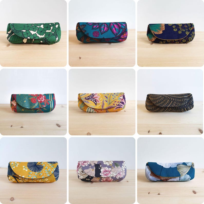 May include: A collection of nine rectangular fabric spectacle cases featuring various patterns and colours, including green floral, teal leaf, navy blue floral, red and green botanical, yellow paisley, black geometric, yellow leaf, floral cat, and blue leaf.