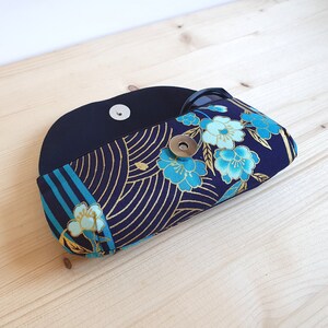 May include: A black and blue fabric eyeglasses case with a floral pattern and a gold snap closure.