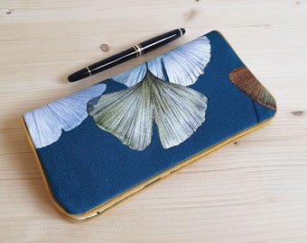 May include: A teal blue wallet with a yellow trim and a floral pattern of white, green, and brown ginkgo leaves.