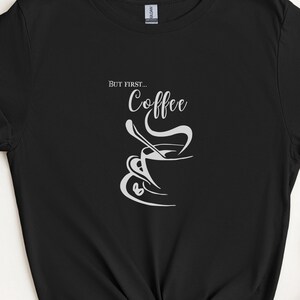 May include: Black t-shirt with white text that reads "But first... Coffee" and a graphic of a coffee cup with steam rising from it.
