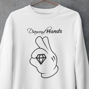 Könnte beinhalten: Weißer Pullover mit einer schwarzen Grafik einer Hand, die einen Diamanten hält, und dem Text "Diamond Hands".