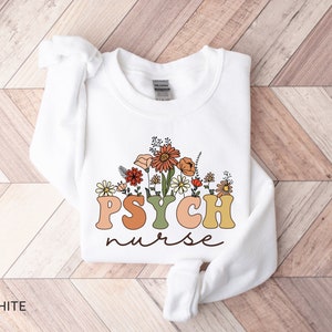 May include: White sweatshirt with a floral design and the text "PSYCH nurse" in colorful retro letters.