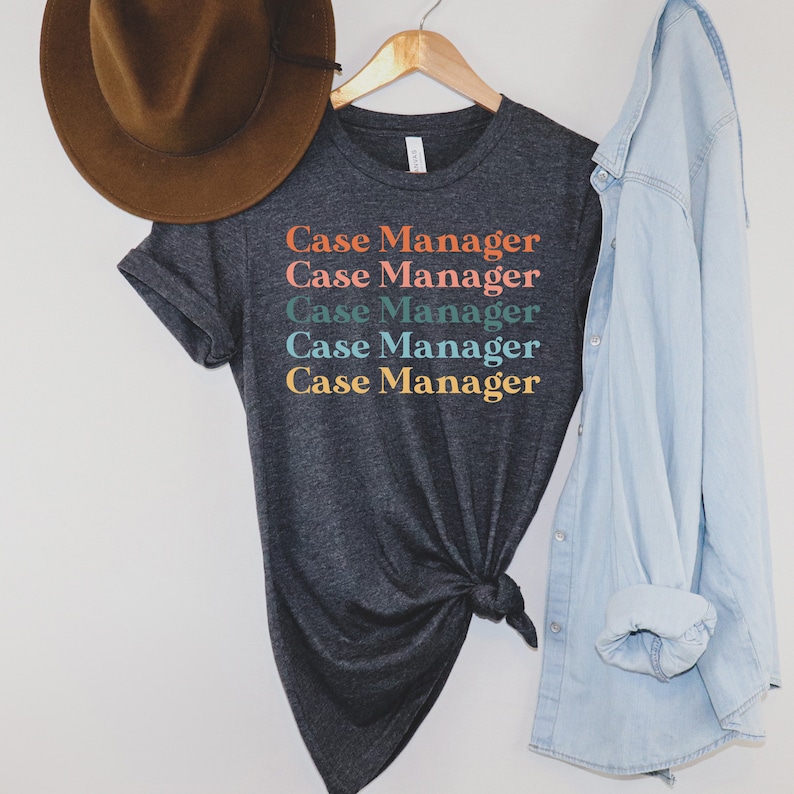 K&ouml;nnte beinhalten: Ein dunkelgraues T-Shirt mit dem Text "Case Manager", der f&uuml;nfmal in verschiedenen Farben wiederholt wird. Der Text ist vertikal gestapelt, wobei jede Zeile in einer anderen Farbe ist: Orange, Rosa, T&uuml;rkis, Blau und Gelb.
