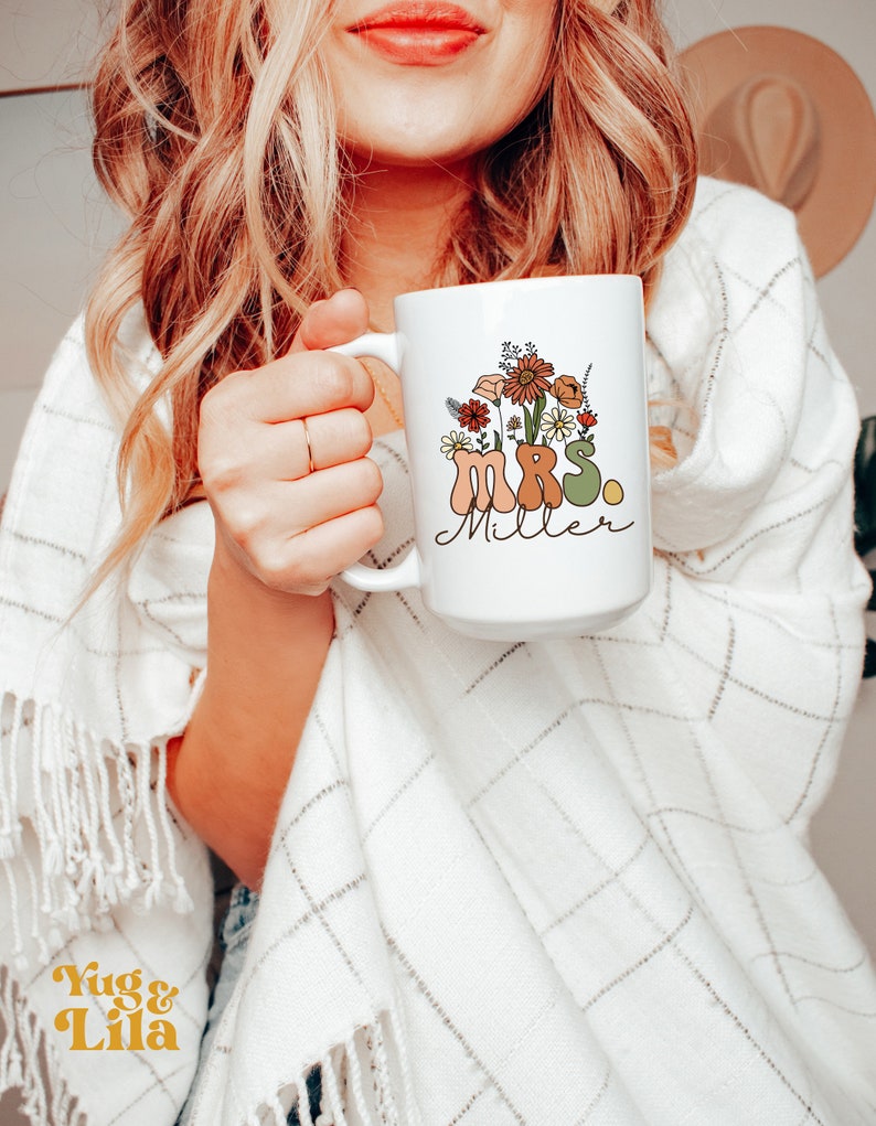 May include: White ceramic mug with a floral design and the text "MRS. Miller" in brown, green, and orange lettering.