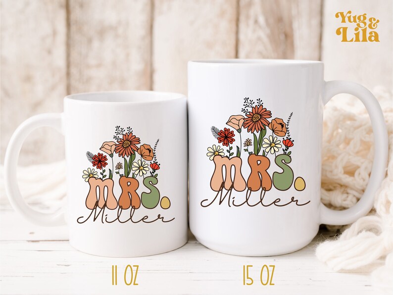 May include: Two white ceramic mugs with a floral design and the text "MRS. Miller" in a retro font. The smaller mug is 11 oz and the larger mug is 15 oz.