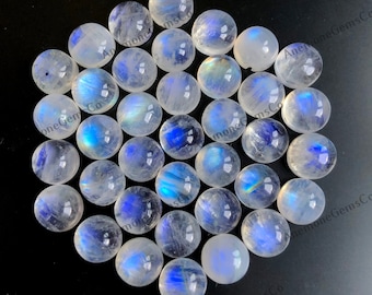 Op de afbeelding: Een verzameling van 25 ronde, witte maansteen cabochons met iriserende blauwe en groene schittering. De stenen zijn ongeveer 10 mm in diameter.