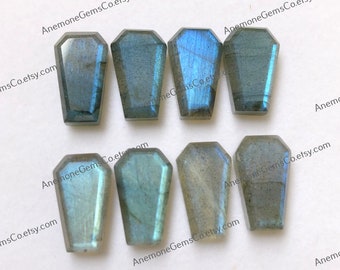 May include: Eight blue-green labradorite gemstone cabochons in a coffin shape. The stones are approximately 1 inch long and 1/2 inch wide.  AnemoneGemsCo.etsy.com