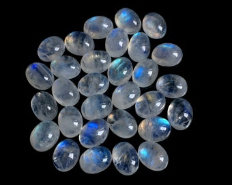 May include: A collection of oval-shaped moonstone cabochons, with a milky white color and iridescent blue and green flashes.