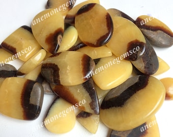 May include: A collection of yellow and brown banded agate cabochons. The stones are smooth and polished, with a variety of shapes and sizes.