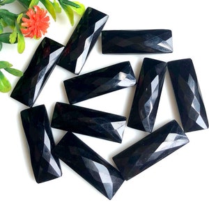 Peut inclure: Plusieurs pierres précieuses noires rectangulaires et facettées. Les surfaces polies reflètent la lumière, disposées sur un fond blanc. Les facettes géométriques rehaussent leur attrait visuel. Idéal pour la création de bijoux.