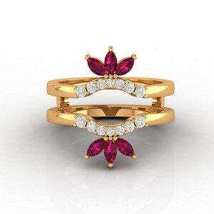 May include: A gold ring with two bands, adorned with a row of small, clear stones and clusters of deep red, marquise-cut stones. The ring has a distinctive, layered design, showcasing a blend of elegance and style.