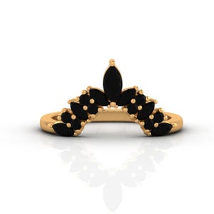 May include: A gold-colored ring featuring a crown design. The ring is adorned with multiple black gemstones, arranged in a floral pattern. The gemstones are marquise-cut, adding a touch of elegance to the jewelry.