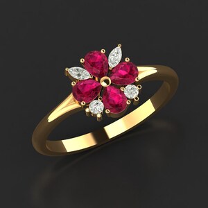 Könnte beinhalten: Ein goldener Ring mit einem Blumenmuster. Der Ring hat fünf rubinrote Edelsteine und sechs kleinere, klare Edelsteine. Das Band ist aus poliertem Gold, und die Edelsteine sind in einem Blumenmuster angeordnet.