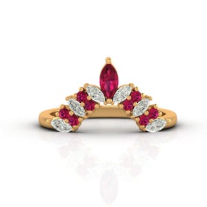 May include: A gold ring with a curved design, set with marquise-cut gemstones. The ring features alternating ruby-red and clear, white gemstones, forming a crown shape. The central gemstone is a larger, ruby-red marquise shape.
