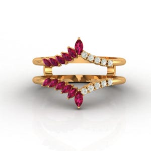 May include: A gold-colored ring with a double band design. The top band features a series of marquise-cut, ruby-colored gemstones, and the bottom band has a row of small, round, clear gemstones. The ring is set against a white background.