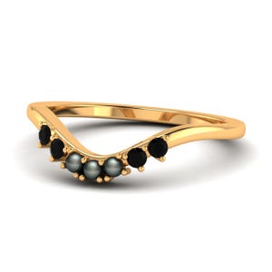 May include: A gold-colored ring with a curved design. The ring is adorned with a series of black gemstones and gray pearls. The gemstones are evenly spaced along the curve of the ring, creating a decorative pattern. The ring is set against a white background.