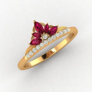 Può includere: Un anello in oro con una disposizione a corona di cinque rubini rossi taglio marquise e una fila di piccoli diamanti bianchi rotondi incastonati lungo la fascia. La struttura in oro giallo è lucida e presenta una finitura liscia.