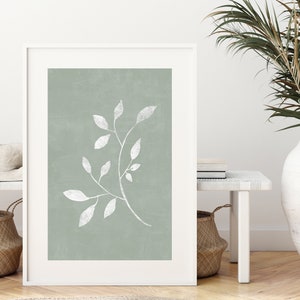 May include: A framed print featuring a white branch with leaves against a sage green background.