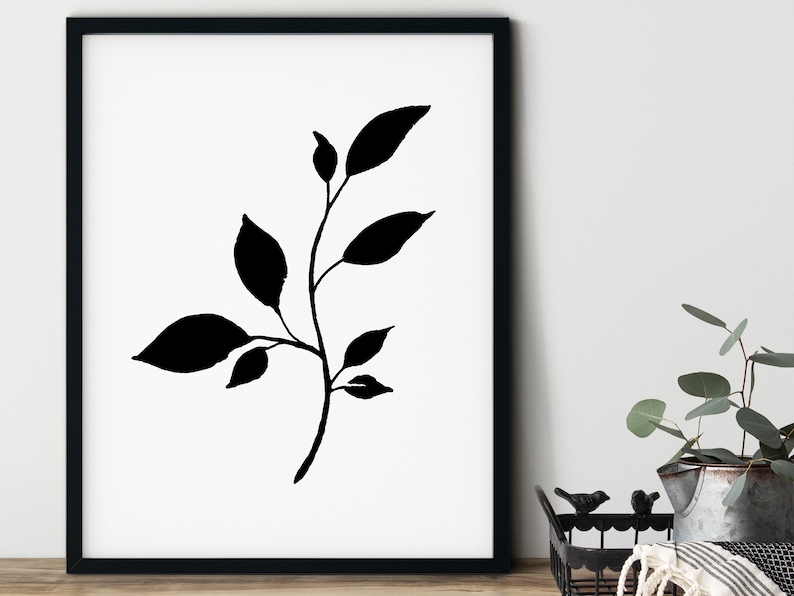 Pode incluir: Silhueta preta e branca de um ramo frondoso com cinco folhas. A imagem est&aacute; emoldurada em uma moldura preta e sobre um fundo branco.