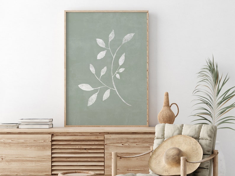 May include: A framed print featuring a white silhouette of a leafy branch against a sage green background.