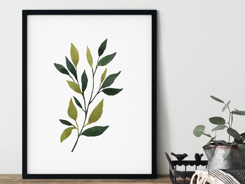 Op de afbeelding: Een aquarel schilderij van een tak met groene en gele bladeren. De tak is afgebeeld in een minimalistische stijl, met een witte achtergrond.