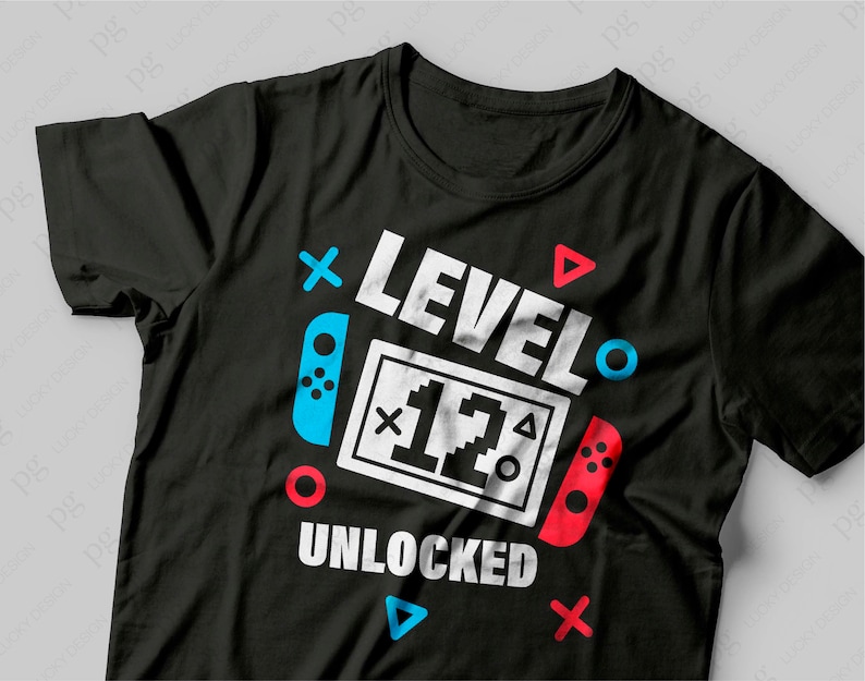 K&ouml;nnte beinhalten: Schwarzes T-Shirt mit einer wei&szlig;en Grafik, auf der "Level 12 Unlocked" mit einem Videospiel-Controller-Design steht.
