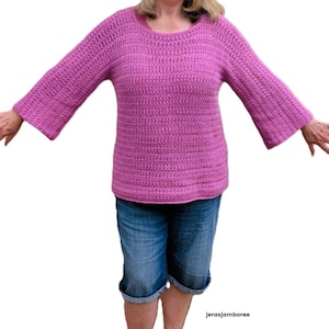 May include: A magenta crochet sweater with long sleeves and a round neckline. The sleeves flare out from the elbow. The sweater is paired with denim shorts. The image includes the text "jerasjamboree".