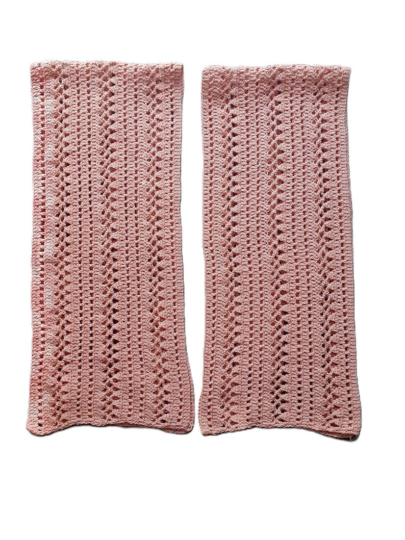 May include: Two pink crocheted rectangular pieces with a lacy pattern.