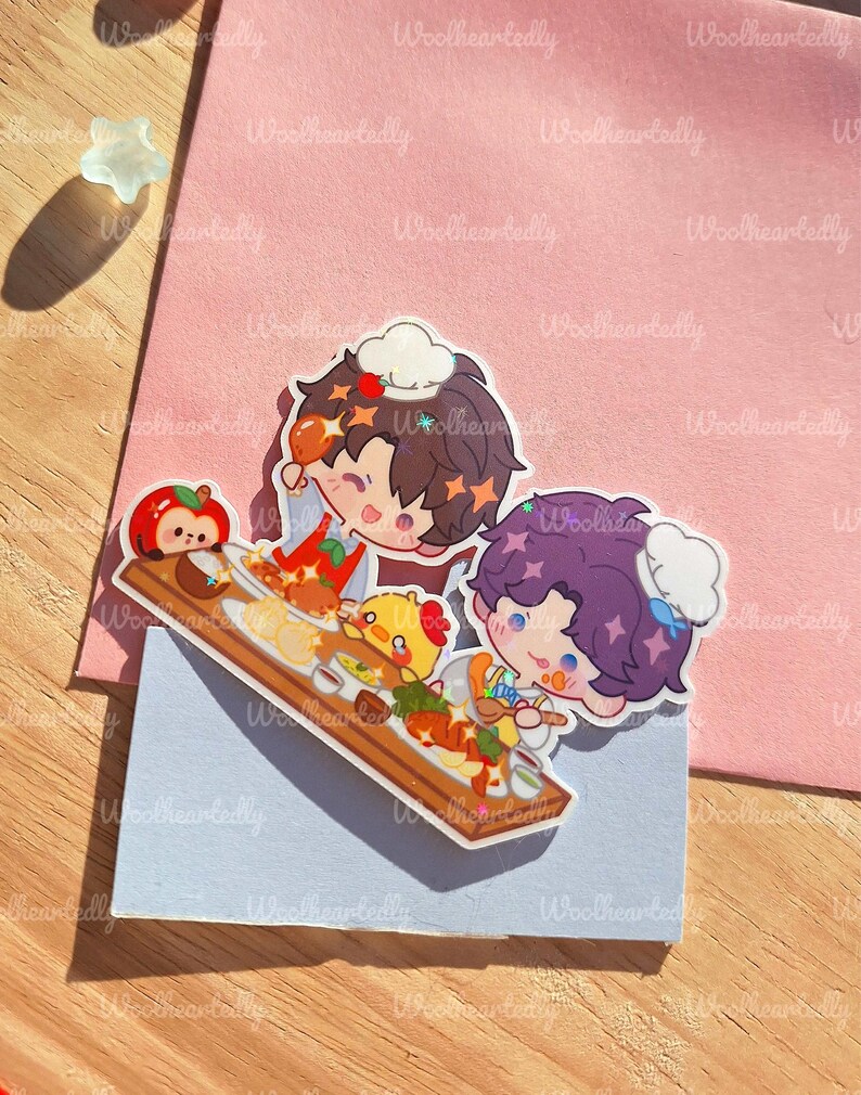 May include: A colorful sticker featuring two cartoon chefs with food on a wooden serving board. The sticker has a light blue background and is placed on a pink envelope. The text "Woolheartedly" is visible.
