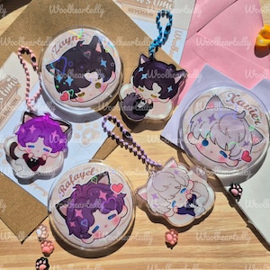Pode incluir: Um conjunto de tr&ecirc;s bot&otilde;es redondos e tr&ecirc;s pingentes de acr&iacute;lico com personagens de estilo anime com orelhas de gato. Os personagens chamados Zayne, Xavier e Rafayel apresentam cabelos coloridos, detalhes hologr&aacute;ficos e pequenos cora&ccedil;&otilde;es.