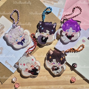 Pode incluir: Cinco porta-chaves de acr&iacute;lico com personagens estilo chibi com orelhas de gato, cada um preso a uma corrente de bolinhas colorida. As personagens t&ecirc;m cores de cabelo distintas, incluindo branco, castanho escuro e roxo, e vestem fatos.