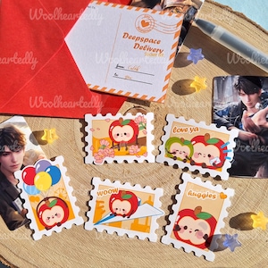 May include: A set of ten colorful stickers featuring cartoon apples with different expressions. The stickers are shaped like postage stamps and have a white border. The stickers feature phrases like "Love ya", "Huggies", and "Wooow".