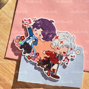 May include: Two cartoon stickers featuring anime-style characters. One character has purple hair and is wearing a blue outfit, while the other has white hair and a red jacket, holding a microphone. Both are surrounded by musical notes and flowers.
