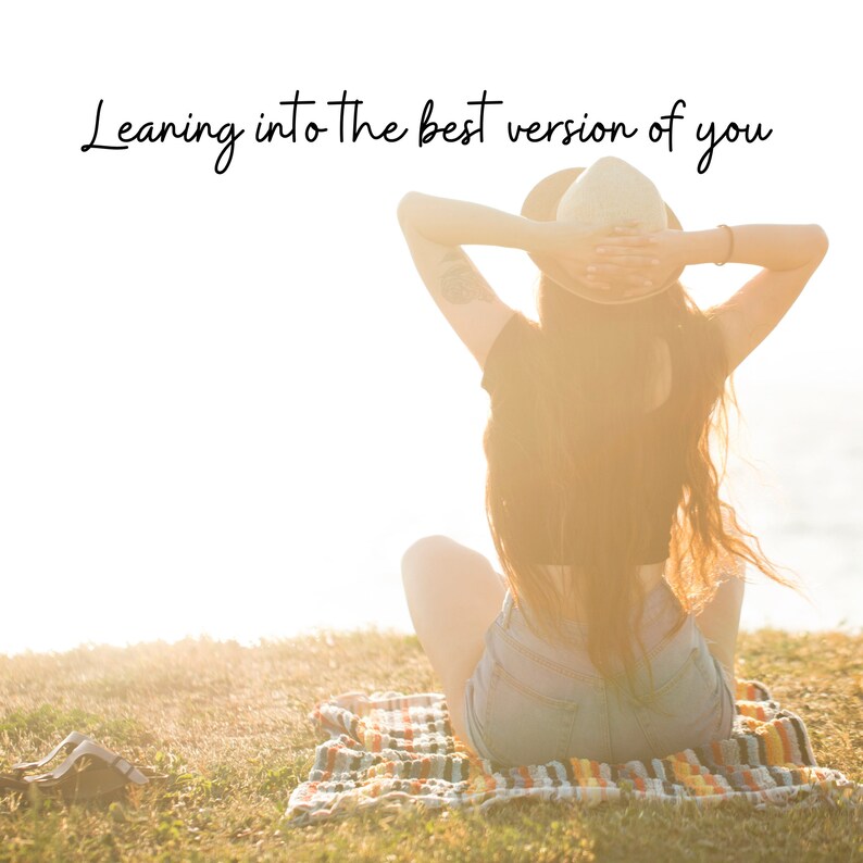 May include: A woman wearing a straw hat sits on a blanket with her arms raised above her head. The text "Leaning into the best version of you" is written above her.