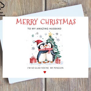 May include: A Christmas card featuring two penguins wearing Santa hats and scarves, standing in front of a Christmas tree. The card reads "Merry Christmas to my amazing husband. I'm so glad you're my penguin."