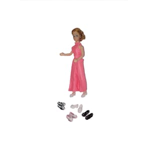 May include: A doll in a pink dress and matching shoes. Several pairs of miniature shoes in various colours, including black, silver, and pink, are scattered around the doll. The doll has blonde hair.