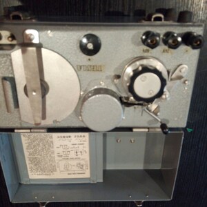 Puede incluir: Un dispositivo de metal gris con un dial redondo, una palanca y una perilla. El dispositivo tiene una etiqueta que dice "V.T.S.S.E.R.I.E." y está etiquetado como "400" y "A.T.". El dispositivo está abierto y muestra una placa de circuito impreso con texto en un idioma extranjero.