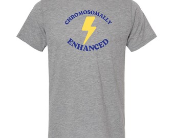 Puede incluir: Una camiseta gris con un gráfico azul y amarillo que dice "Chromosomally Enhanced" con un rayo en el centro.