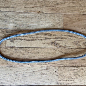 May include: A gray rope laid out in a circle on a wooden floor.