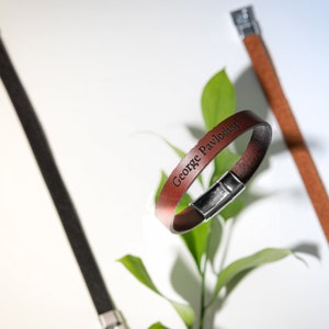 Peut inclure: Un bracelet en cuir marron avec une fermeture en argent. Le bracelet est gravé du nom "George Pavlodia".