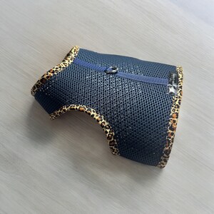 May include: A blue mesh dog harness with a leopard print trim. The harness has a blue strap and a silver clip. The text "Happy Dog" is printed on the strap.