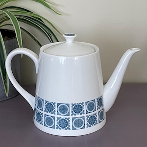 May include: White ceramic teapot with a blue and white geometric pattern. The teapot has a lid and a spout.