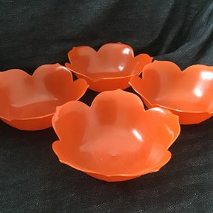 May include: Set of four orange plastic bowls with a flower-shaped design. The bowls are ideal for serving snacks or dips.