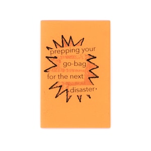 May include: A rectangular orange booklet with a black hand-drawn starburst graphic on the cover. The text printed in black inside the starburst reads: prepping your go-bag for the next disaster. The cover has a matte finish and clean edges.