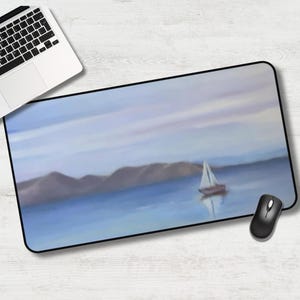 May include: Rectangular mousepad featuring a serene seascape painting with a sailboat on the water. The artwork has a soft, watercolor-like quality with shades of blue, purple, and white. A black mouse and a laptop are visible.