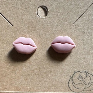 Könnte beinhalten: Ein Paar rosa Harzohrringe in Form von Lippen.