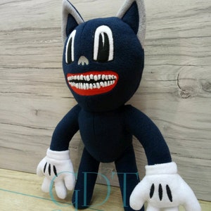 May include: A blue cartoon cat plush toy with a large toothy grin and white gloves. The toy has large black eyes and a gray nose. The toy is standing on a wooden surface.