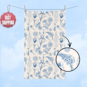 May include: A cream-colored towel with a blue floral pattern, including tulips, irises, and other flowers. The towel is hanging on a clothesline. A circular inset shows the text "FUCK TRUMP".